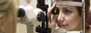 Optometrist performing a diabetic eye exam with a slit lamp on a female patient
